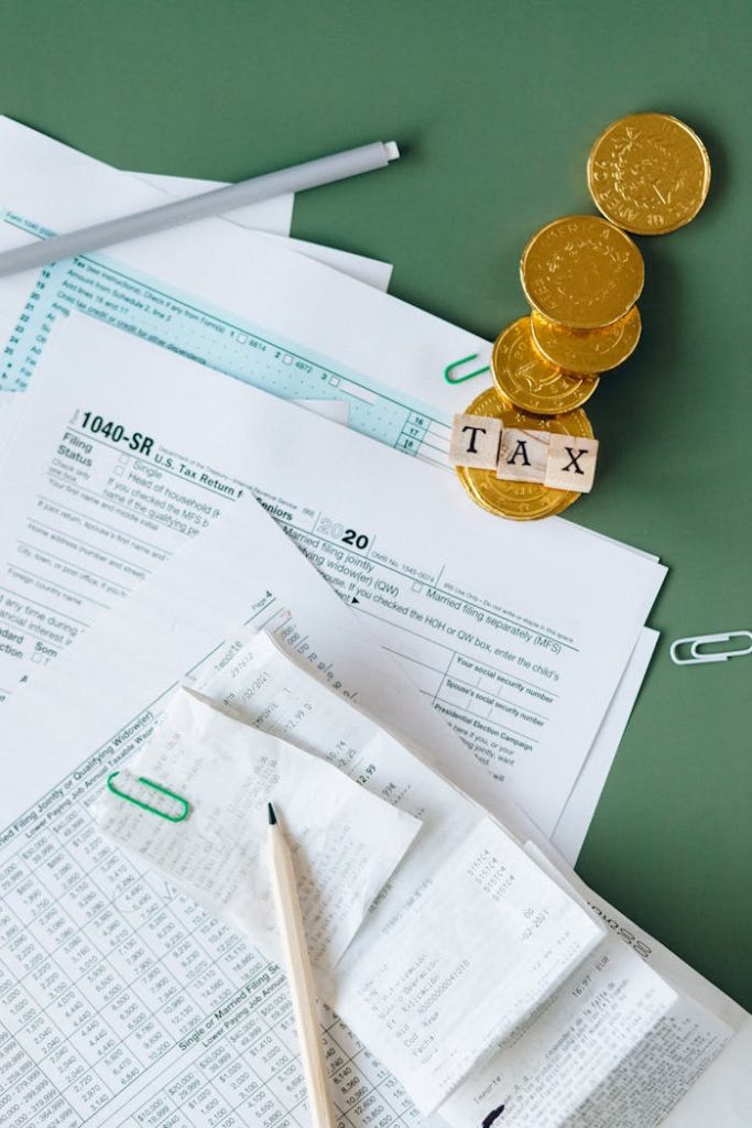 Mastering the First Impression: Your intriguing post title goes here Tax documents and gold coins on a green desk symbolizing financial planning and savings.